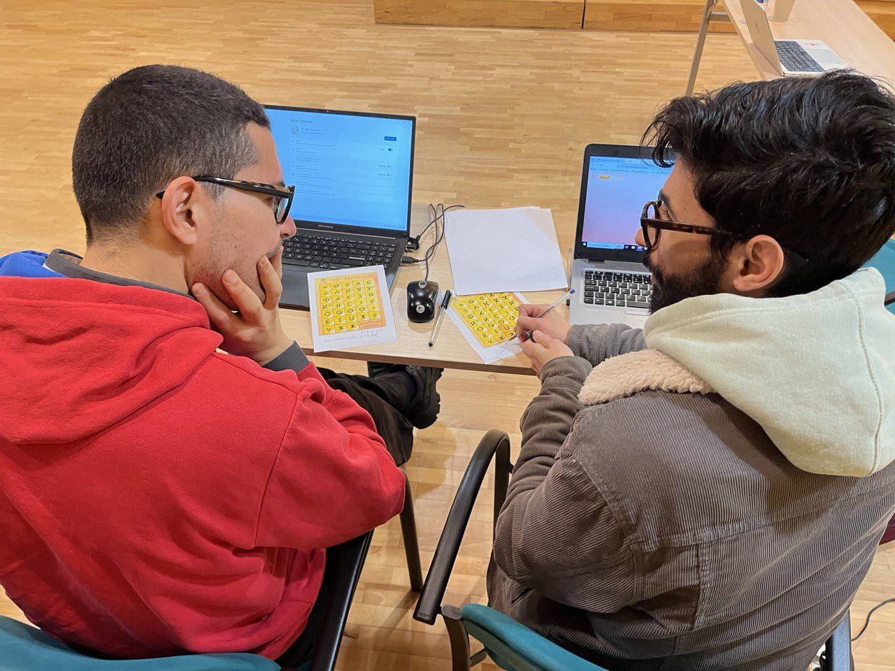 Dos col·laboradors discuteixen a la datathon d'Awal sobre diferents guions de Tamazight